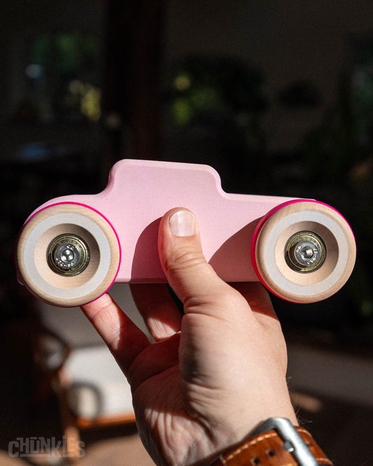 Hand held Chill Pepper Chunkies No04  Wooden Toy Car The Hot Rod Perfectly Pink to show scale. These solid wooden toy cars are much bigger than usual and due to the solid build with stainless steel heavy duty hardware and real skate bearings for a smooth ride these cars cars ride like no other. Made in Europe
