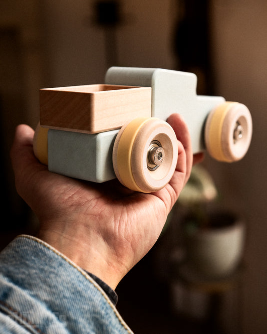 Handheld light blue wooden toy truck made by Chill Pepper called the Chunkies Model number 02 the "workhorse" pick-up truck. Guaranteed long lasting play time. Made in Europe from sustainable solid wood. With its big wooden wheels, real skate bearings and stainless steel hardware it's ready for any adventure.